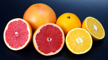 cut pieces of different citrus fruits on dark background