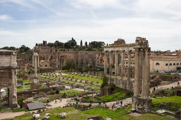 Fototapeta premium Top view of the Roman forum, illuminated by the sun, against a blue sky. Ancient architecture and urban landscape of historical Rome.