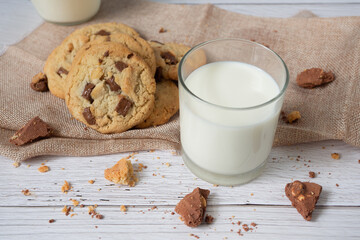 Delicious homemade chocolate chip cookies, paired with fresh milk in a glass and pitcher, placed on a white wooden floor and a blue background cloth. Drink in the morning for health and strong bones.