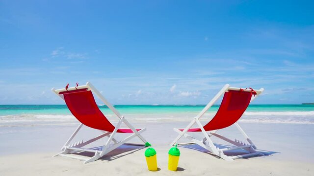 Hawaii beach background. Beach chairs with cocktails on the white sand near the blue sea.