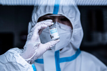 開発したワクチンを見つめる防護服を着た研究員	
