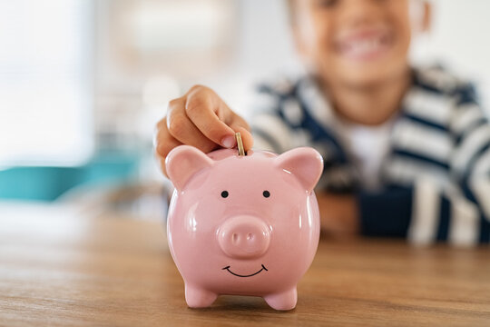 Smiling child saving money in piggybank