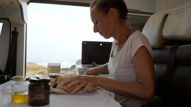 Young Woman Having A Fresh Cup Of Coffee In Her Camper Van Enjoys Coastal Views From Her Vehicle. Female Solo Traveller Living In Her Van Drinking Coffee In The Morning 