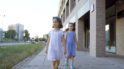 two cute little girls are walking along the city streets at sunset - Powered by Adobe