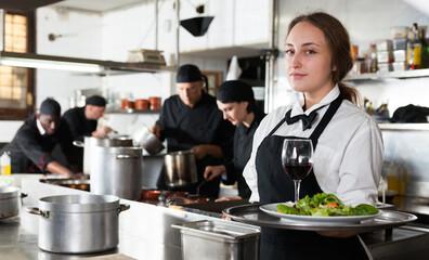 Professional waitress holding serving tray at restaurant kitchen. High quality photo