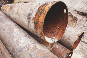 Fragments of old large water pipes. After many years of operation, corroded metal pipe destroyed. Rusty steel tube with holes metal corrosion. Selective focus.