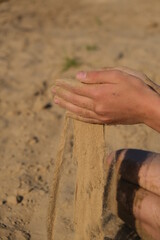 Hand clasping golden sand falling through the finger, with place for text
