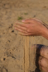 Hand clasping golden sand falling through the finger, with place for text
