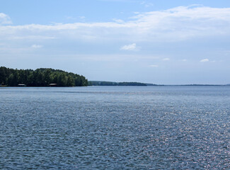 Forest lake trees landscape. Lake view in summer. Sun glare on the water surface. Selective focus.