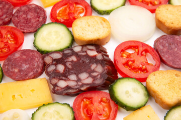 sliced ​​pieces of sausage, salami, cheese, cucumber and tomato. fast food. ingredients for pizza. calories and diet