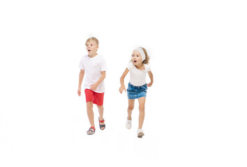 Fototapeta na wymiar Energy. Happy kids, little emotional caucasian boy and girl jumping and running isolated on white background. Look happy, cheerful, sincere. Copyspace for ad. Childhood, education, happiness concept.