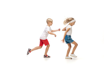Fototapeta na wymiar Fun. Happy kids, little emotional caucasian boy and girl jumping and running isolated on white background. Look happy, cheerful, sincere. Copyspace for ad. Childhood, education, happiness concept.