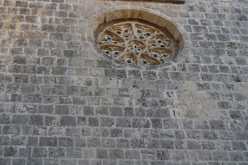 A grey stone wall with a round carved window in Bellapais Abbey. Kyrenia. Cyprus.