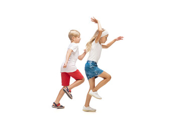 Fototapeta na wymiar Step by step. Happy kids, little emotional caucasian boy and girl jumping and running isolated on white background. Look happy, cheerful, sincere. Copyspace for ad. Childhood, education, happiness