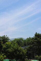Obraz premium View of trees, a house with a tiled roof and mountains against a blue sky. Xian. China.