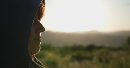 The movement of the camera to the left changes the focus to a young woman with a hood looking forward. In the background of the mountain