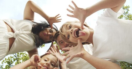 Happy family taking selfie or recording video leaning over the camera grimacing and showing tongues during summer vacation.