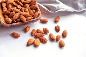 Almonds nuts in wooden bowl on a white wooden table
