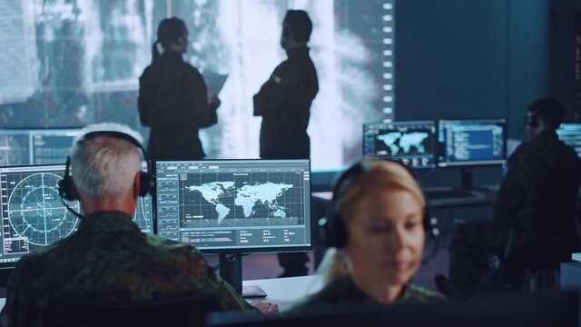 Shifting Focus Between Military Surveillance Officers Working in a Central Office Hub for Cyber Operations, Control and Monitoring for Managing National Security, Technology and Army Communications.