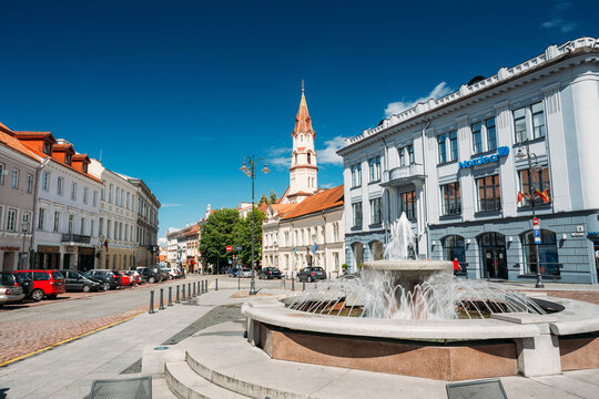 Vilnius, Lithuania. Town Hall Square Fountain In Rotuses Square In Old Town. St. Nicholas Church In Sunny Summer Day. Popular Touristic place