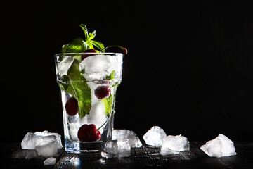 Refreshing cherry drink with ice. Seasonal lemonade. Photo on a black background. Copy of the space.