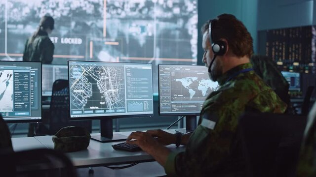 Military Surveillance Officer Working on a City Tracking Operation in a Central Office Hub for Cyber Control and Monitoring for Managing National Security, Technology and Army Communications.