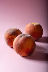 Juicy fresh peaches on a pink background.