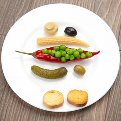 salad of canned and pickled olives, mushrooms, corn, peas, cucumber and red pepper on a white plate.  food and vegetables. diet and weight loss