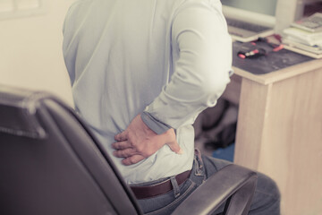 Asian young man officer  has pain back and headache from working
