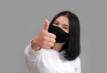 Asian women show thumb up and wearing mask trying to protect from coronavirus epidemic.