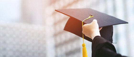 close up graduate hand hold show hat in background school building. Shot of graduation cap during...