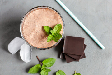 Top view of a chocolate cocktail, smoothie with ice, chocolate pieces and mint in a glass glass....