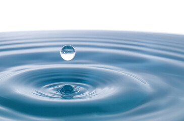Water droplets fall down closely into the dark blue water, making it the perfect center in nature. Isolated on white background