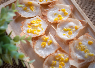 Close up Knmcrk made from coconut milk with sugar and flour corn topping, Thai dessert placed on wooden plate.