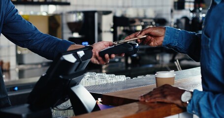 Close up of hands of multiethnic bartender and client men. African American male client paying with paypass on credit card. Mixed-races. Passing payment at counter. Pay for drink or food in cafe.