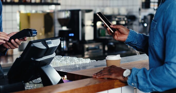 Close up of hands of multiethnic bartender and client men. African American male client paying with paypass on credit card. Mixed-races. Passing payment at counter. Pay for drink or food in cafe.