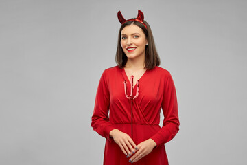 holiday, theme party and people concept - happy smiling woman in red halloween costume of devil...