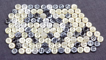 Plastic shiny buttons for clothes on a fabric background. Fashion and clothing. Factory industry.