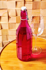 Vintage wine bottle from pink glass and long wine glass on the wooden table. Winery cellar and...