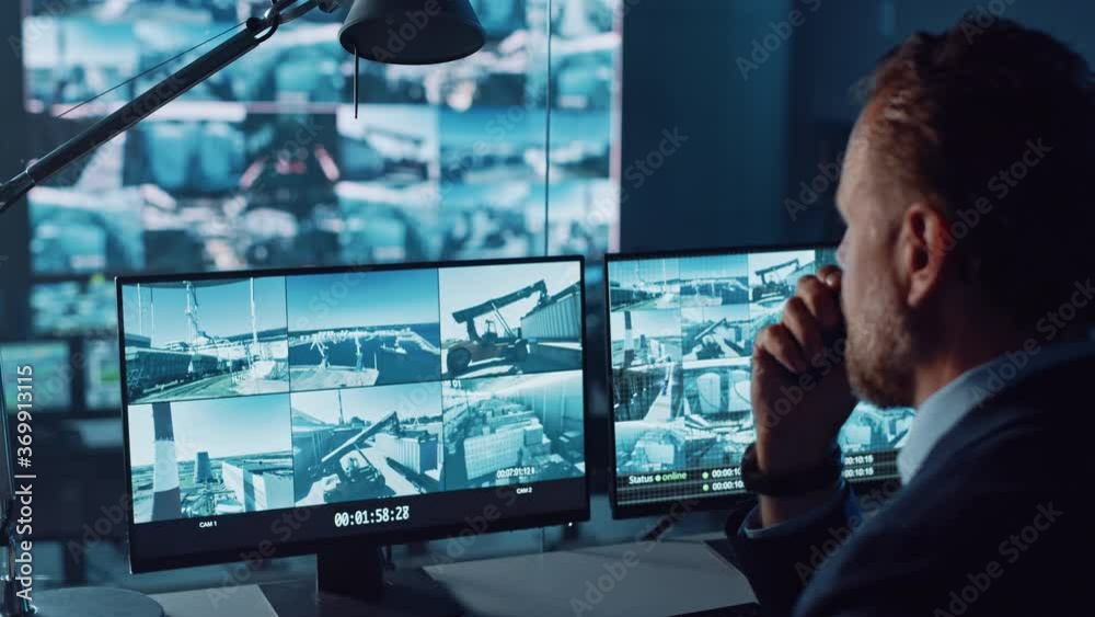 Leinwandbilder male officer works on a computer with surveillance cctv video footage in a harbour monitoring center