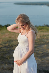 Fototapeta na wymiar Pregnant woman in white dress posing in the park