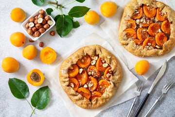 Healthy pastries made from rye flour, dessert diet food. Galette with apricots and nuts on a light stone table. Top view flat lay background.