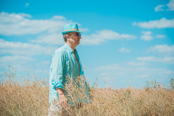 Mature man at field, lifestyle older men. Older senior man wear blue skirt and hat, casual style at field