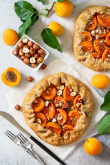 Healthy pastries made from rye flour, dessert diet food. Galette with apricots and nuts on a light stone table. Top view flat lay background.