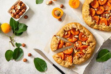 Healthy pastries made from rye flour, dessert diet food. Galette with apricots and nuts on a light stone table. Top view flat lay background. Copy space.