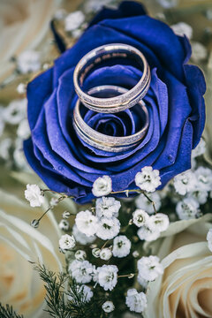 Eheringe auf blauen Rosen im Brautstrauß. Vintage Look im Hochformat