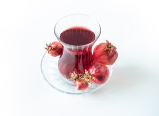 Turkish pomegranate tea in a glass cups isolated on white background, close-up. Traditional herbal tea with flowers and fruit of pomegranate in Turkey.