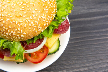 Hamburger with vegetables and sausage. Fast food and breakfast. Calories and diet.