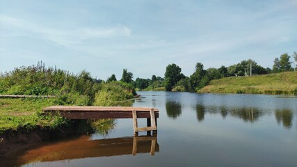 wooden bridge near the lake against the blue sky on a sunny day