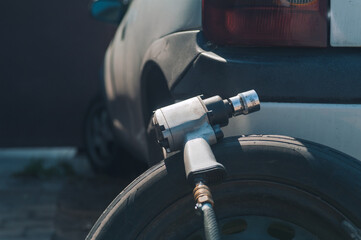 Pneumatic wrench on a wheel against the background of the machine. Car maintenance and repair in the garage.